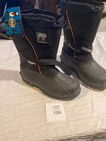 Full side view of the pair of black Pathfinder brand winter boots with orange piping and rubber sole, new with tag.