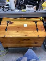 Top-down view of the wooden chest showing the top lid with dark metal decorative hinges and a tape measure indicating the length is about 38 inches.