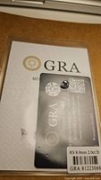 Clear photo showing the 2ct 8mm certified moissanite stone with its GRA certification card for authenticity and grading.