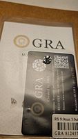 Photo showing GRA certification card and moissanite gem, confirming 9.0mm 3.0 carat size with VVS1 clarity and D color.