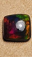 Front close-up of the cushion-shaped Ethiopian black opal with vivid multicolor flash.