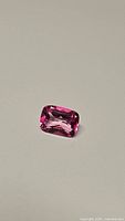 Top-down view of cushion cut hot pink topaz on white background