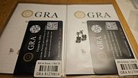 Certified moissanite stud earrings placed next to their GRA certification card, showing 6.5mm 1.0ct D color details.