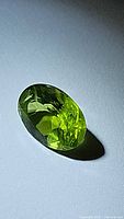 Close-up photo of the oval cut natural Peridot gemstone showing its apple green color and internal clarity.