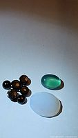 Photo showing seven round black onyx beads, one oval blue chalcedony, and one oval green onyx gemstone.