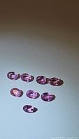 Eight pink oval gemstones arranged on white background