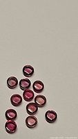 Photo showing 13 round cabochon natural pink sapphires in shades of raspberry and orange-pink.
