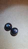 Two jet black round cabochon star diopside gemstones with sharp star asterism effect visible on the domed surface under lighting.