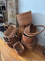 Photo showing a stacked assortment of woven baskets near a fireplace, various shapes and handles visible.