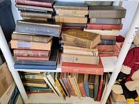 Top view of two shelves stacked with hardcover books and some paperbacks in varied sizes and colors, showing wear and tear.