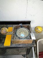 Compass and wooden storage box open on tabletop with yellow sphere attachments mounted on rods.