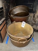 Three copper buckets displayed in a stone fireplace: one hammered bucket at back, two smooth buckets stacked at front.