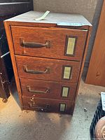 Frontal image showing the four drawers with metal pull handles and brass label holders on each drawer front.