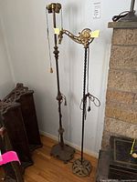 Two metal floor lamps standing side by side, showing full height and bases