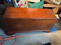 Full front view of the wooden hope chest showing front panel, base molding, and top surface with scratches.