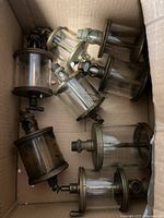Top-down view of 7 mechanical oil cups in cardboard box showing glass cylinder and brass fittings.