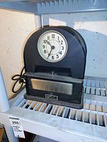 Front view of black Simplex time clock with white clock face and visible branding plate.