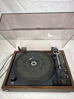 Full view of BIC Belt Drive 1000 turntable with plastic dust cover closed showing unit in wood case frame.