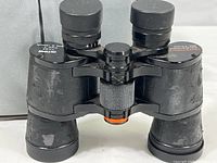Front and top view of Celestron Ultima binoculars showing worn rubberized grips and central focus wheel.