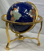 Front view of globe showing deep blue lapis oceans and polished brass gimbal stand