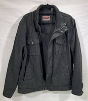 Front view of Levi's black denim jacket showing Levi’s label, front pockets, and zipper with snap button closure.