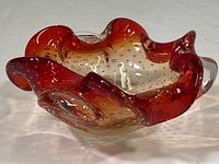 Three angled views of the Murano art glass candy dish highlighting the red to clear gradient coloration, undulating wavy edge, and suspended bubbles inside the glass.