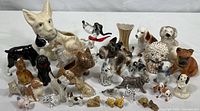 Wide view of the entire collection showing varied vintage ceramic and glass dog figurines of many breeds, including a large dog head planter and multiple small detailed dog figurines in different colors and finishes.