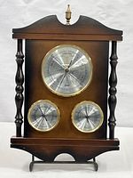 Full front view of vintage 3-dial wood weather monitor showing entire wooden frame, three metal dials, and finial top