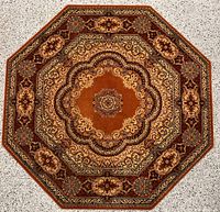 Top-down photo showing the full octagonal wool rug with central medallion and border patterns in warm brown, gold, and burgundy tones.