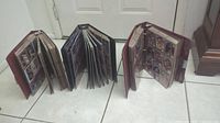 Three large binders of sports cards opened and standing upright on floor.