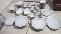 The full 77-piece Noritake Sharon's Dream patterned china set arranged on an outdoor surface showing all included items.