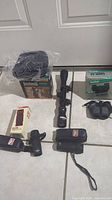 Photo showing the Bushnell boxed binoculars, Bushnell powerline scope, Vivitar boxed monoculars, and multiple other small optics devices on the floor.