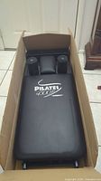 Top view of Pilates 4500 JP workout unit showing padded backrest and folding frame inside a box.