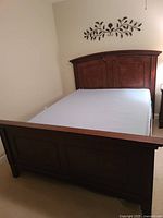Full view of queen size bed showing wooden headboard and footboard with mattress