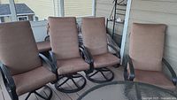 Four brown high back chair cushions arranged on outdoor metal chairs