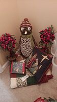Lot contents arranged on floor: pine berry topiaries, woven penguin with red striped hat and scarf, boxed nativity figurines, Christmas pillow and quilt.