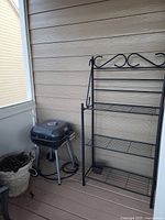 Photo of the Gibson Home grill, black metal baker's rack, and beige plant pot from the side.