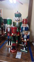 Five wooden nutcrackers arranged in front of a mirror showing varying heights and colorful designs