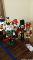 Full view of the five wooden nutcrackers showing variety in uniforms and headwear, arranged on a wooden surface.