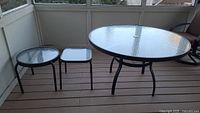 Three patio tables grouped together showing size comparisons and glass tops on each.
