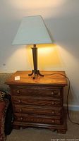 Full view of the side table with the lamp on top, showing the wood grain and lamp shade.
