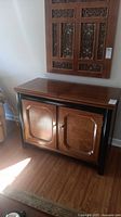 Front view of the Thomasville wooden bar cabinet with closed doors and brass hardware.