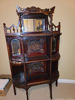 Front view showing entire etagere with carved details and mirrored panels