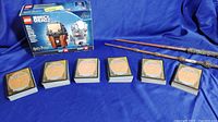 Photo of LEGO BrickHeadz Harry Potter set box, two magic wands, and stacks of Magic The Gathering cards showing reverse sides.