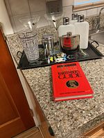 Photo showing the bar tray and all included accessories arranged, including glasses, bottles, flask, measuring tools, and bartenders guide.