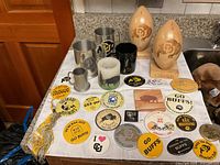 CU Buffalo fan memorabilia spread out on a table including commemorative buttons, mugs, wooden decor footballs, candle with buffalo image, and other CU themed items.