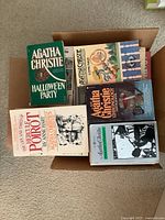 Top view of a cardboard box filled with Agatha Christie paperback mystery novels showing titles on top including 'Hallowe'en Party', 'Sleeping Murder'