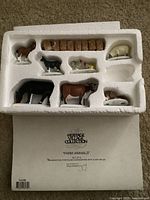 Set of 8 farm animal figurines arranged in white styrofoam packaging, including horse, cow, sheep, donkey, and accessories.