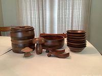 Full set arranged showing large serving bowl, stacked salad bowls, storage container, two small mushroom-shaped decor pieces, and wooden salad servers on white table.