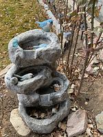 Front view of the four-tier fountain with bird figures showing the basin details and leaf debris inside basins.